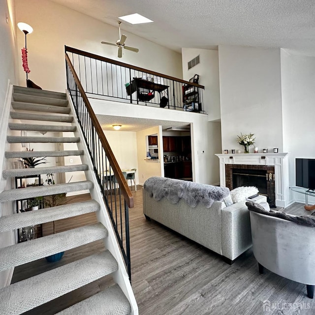 living area featuring visible vents, wood finished floors, a skylight, a fireplace, and stairs