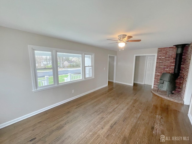 66 W Spring St W, Somerville, NJ 08876 - unfurnished living room featuring wood finished floors, a wood stove, a ceiling fan, and baseboards