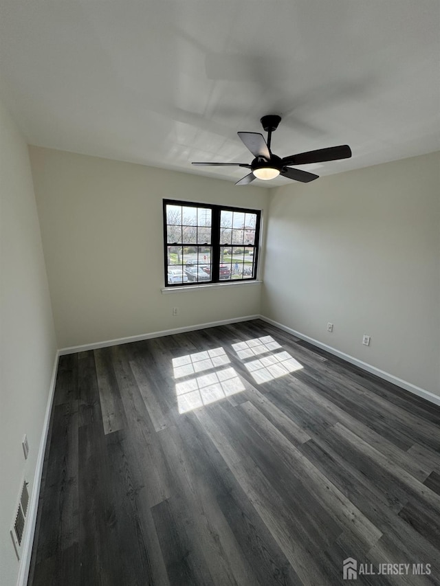 spare room with dark wood finished floors, ceiling fan, and baseboards