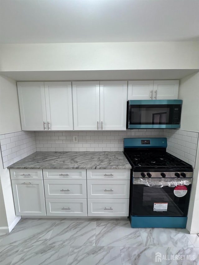 89 Golden Sq, Woodbridge Proper, NJ 07095 - kitchen featuring stainless steel appliances, light marble finish floors, white cabinetry, light stone countertops, and backsplash