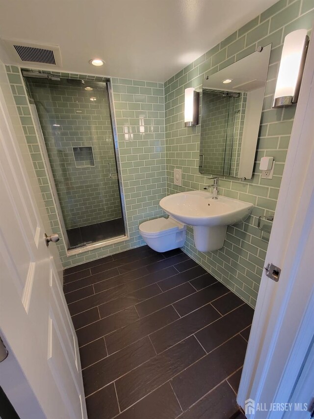 bathroom featuring tile patterned flooring, an enclosed shower, sink, and tile walls