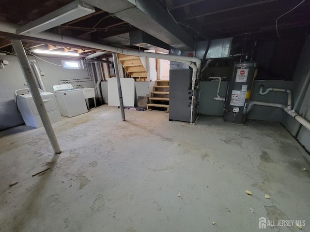 basement featuring water heater, fridge, heating unit, and independent washer and dryer