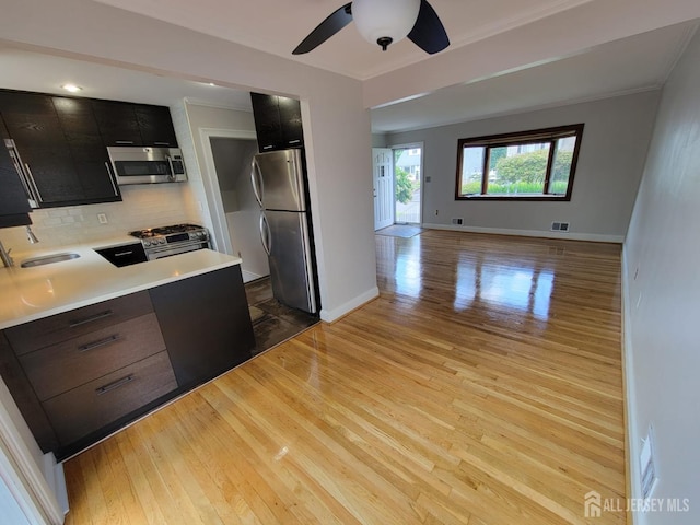 kitchen featuring sink, appliances with stainless steel finishes, ceiling fan, light hardwood / wood-style floors, and decorative backsplash