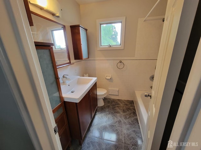 full bathroom with washtub / shower combination, toilet, tile walls, vanity, and tile patterned flooring