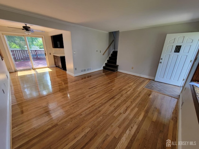 unfurnished living room featuring hardwood / wood-style flooring, ornamental molding, and ceiling fan