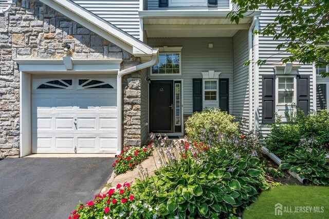 43 Capica Ct, South Amboy, NJ 08879 - doorway to property with stone siding, a garage, and driveway