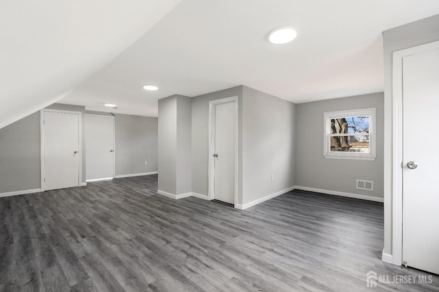 bonus room featuring visible vents, baseboards, dark wood-style flooring, and lofted ceiling