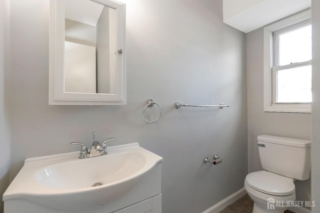 half bath featuring toilet, vanity, and baseboards