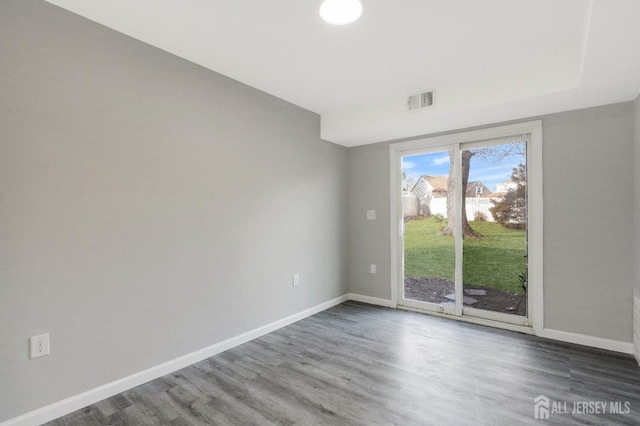 unfurnished room featuring visible vents, wood finished floors, and baseboards