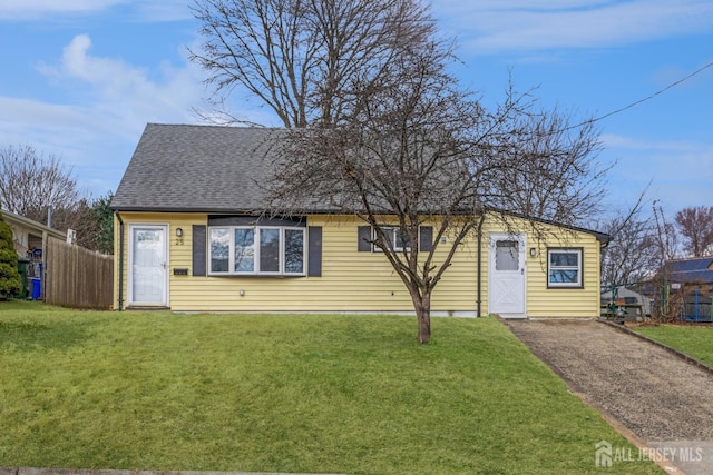 view of front of property featuring a shingled roof, a front lawn, and fence