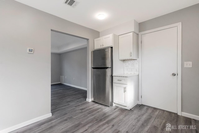 kitchen featuring visible vents, wood finished floors, white cabinetry, freestanding refrigerator, and decorative backsplash