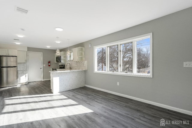 kitchen featuring dark wood-type flooring, a sink, backsplash, stainless steel appliances, and light countertops