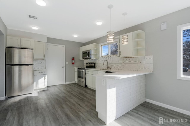 kitchen featuring visible vents, open shelves, stainless steel appliances, a peninsula, and light countertops