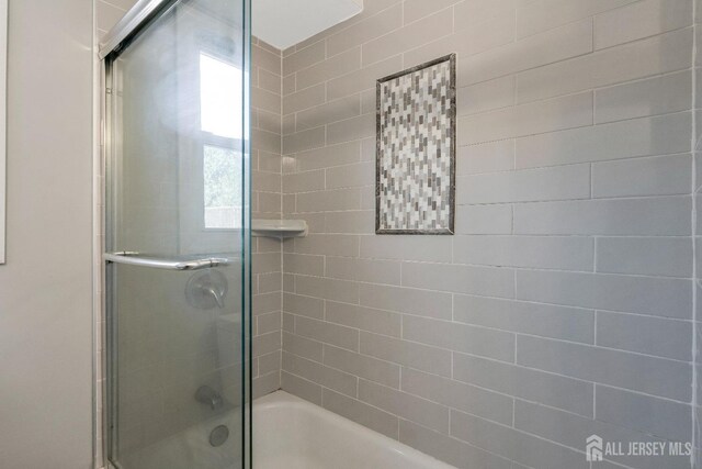 bathroom featuring combined bath / shower with glass door