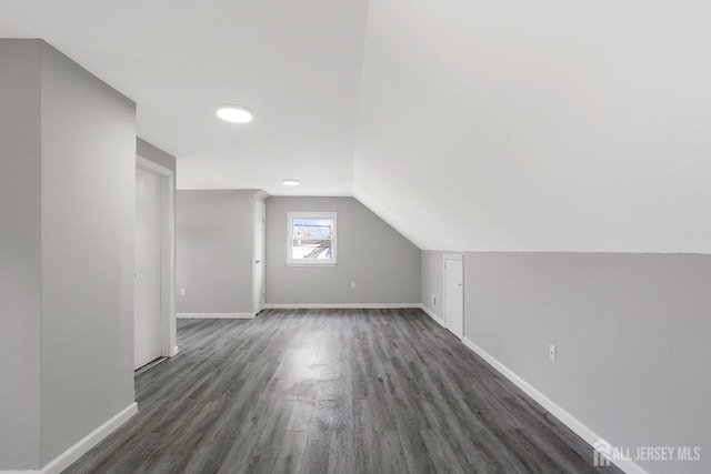 bonus room featuring baseboards, lofted ceiling, and dark wood-style floors