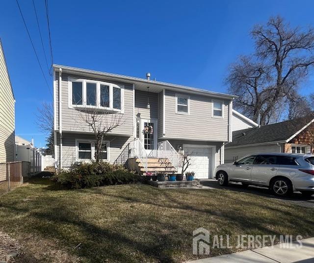 bi-level home with a front lawn, an attached garage, and fence