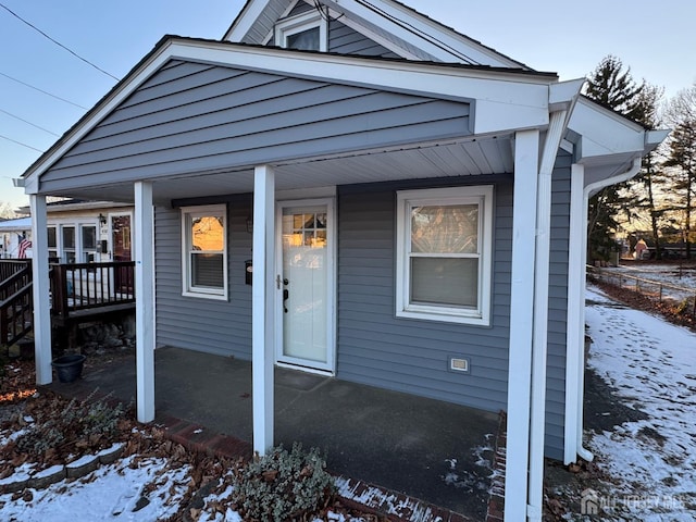 snow covered property entrance featuring a porch