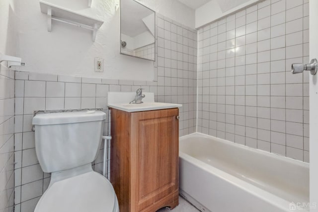 full bathroom with tile walls, vanity, tiled shower / bath combo, and toilet