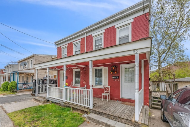 view of front of home featuring brick siding and a porch