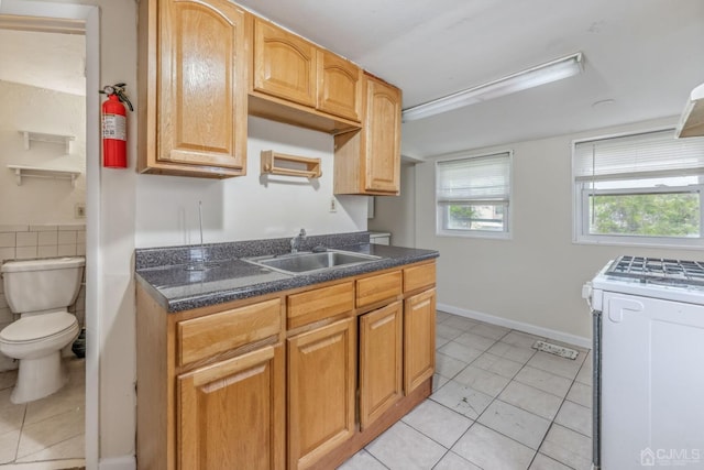 kitchen featuring a sink, white gas stove, and light tile patterned flooring
