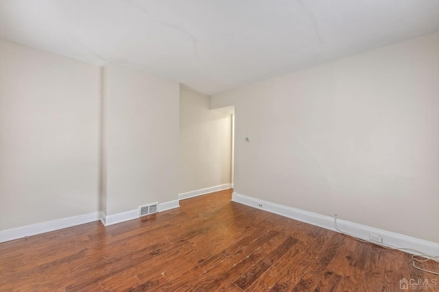 unfurnished room featuring visible vents, baseboards, and wood finished floors