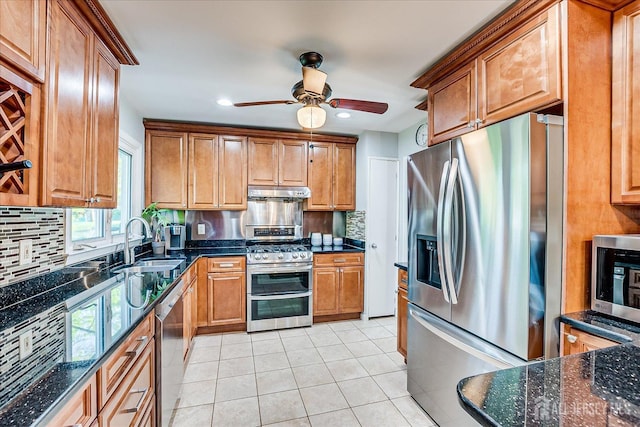 kitchen with appliances with stainless steel finishes, a sink, under cabinet range hood, tasteful backsplash, and ceiling fan