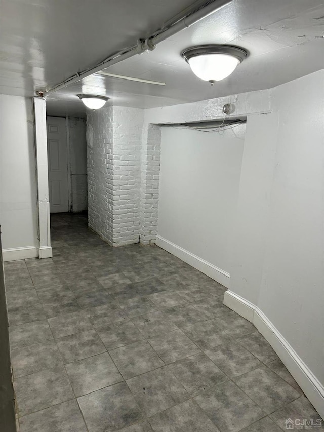 finished basement featuring brick wall and baseboards