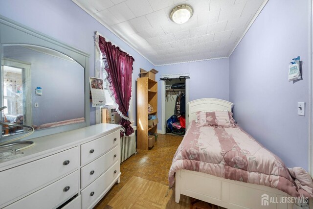 bedroom featuring light parquet floors, ornamental molding, and a closet