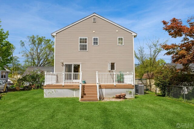 rear view of house featuring central air condition unit, a lawn, and a deck