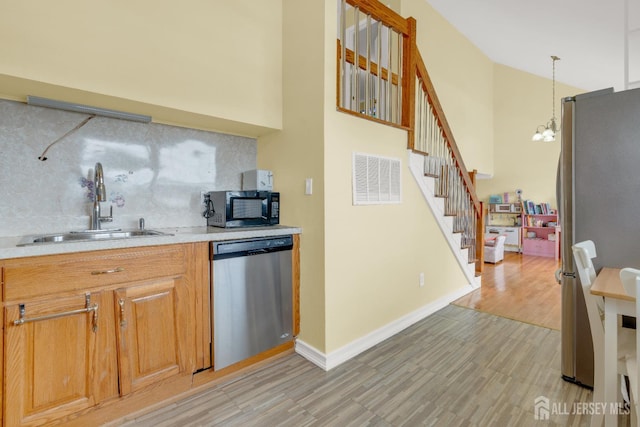 186 Tyler Ave, Iselin, NJ 08830 - kitchen featuring appliances with stainless steel finishes, backsplash, light countertops, light wood-type flooring, and a chandelier