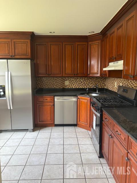 21 Rice Run, East Brunswick, NJ 08816 - kitchen with appliances with stainless steel finishes, a sink, under cabinet range hood, light tile patterned floors, and dark countertops