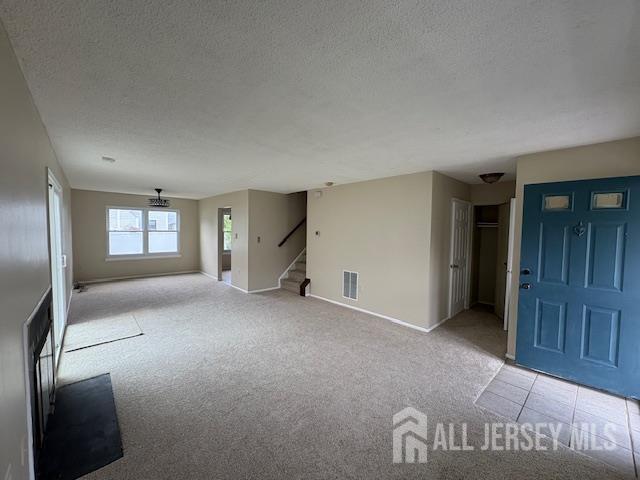 21 Rice Run, East Brunswick, NJ 08816 - unfurnished living room with light carpet, a textured ceiling, baseboards, and stairs