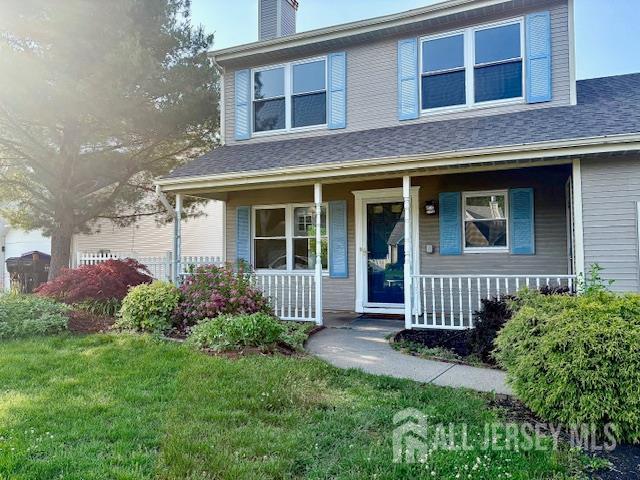 21 Rice Run, East Brunswick, NJ 08816 - view of front of house with covered porch, a chimney, and a front yard