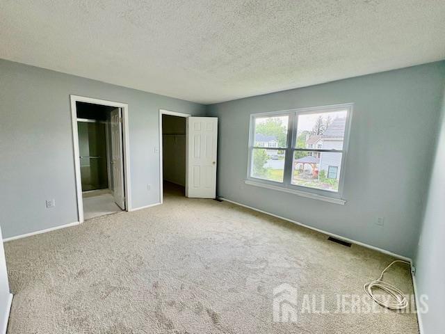 21 Rice Run, East Brunswick, NJ 08816 - unfurnished bedroom featuring carpet flooring, baseboards, a textured ceiling, connected bathroom, and a spacious closet