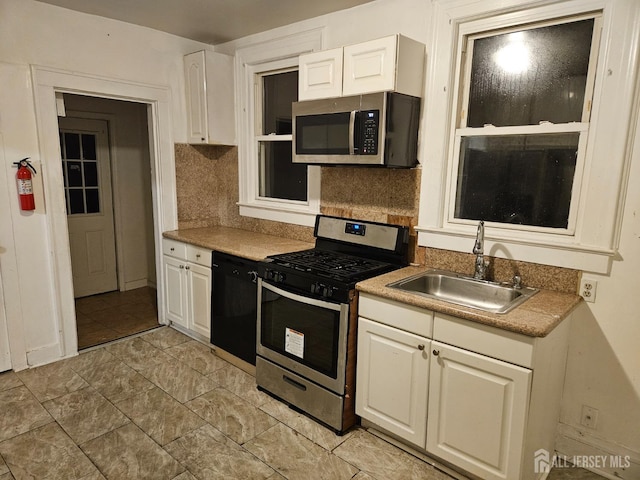 kitchen with sink, white cabinetry, appliances with stainless steel finishes, decorative backsplash, and light tile patterned floors