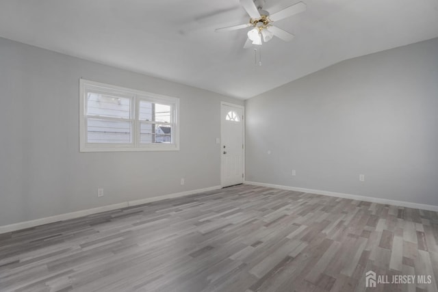 empty room with light wood-style floors, baseboards, vaulted ceiling, and a ceiling fan