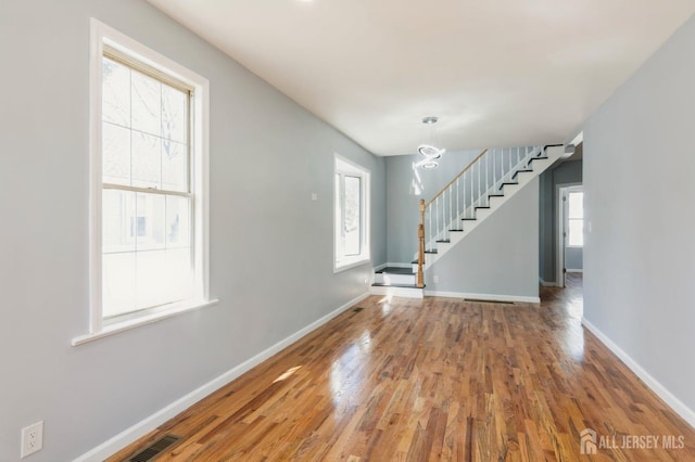 interior space featuring plenty of natural light, wood finished floors, stairway, and baseboards