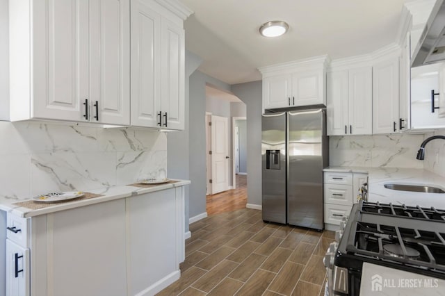 kitchen with stainless steel fridge with ice dispenser, a sink, range with gas stovetop, and white cabinetry