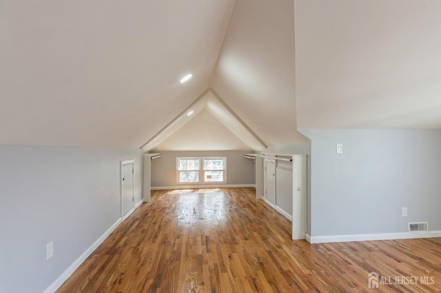 bonus room with vaulted ceiling, baseboards, visible vents, and wood finished floors