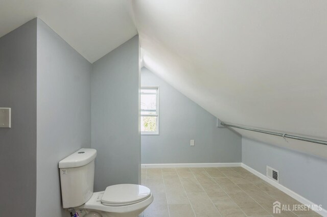 bathroom with lofted ceiling, toilet, and visible vents