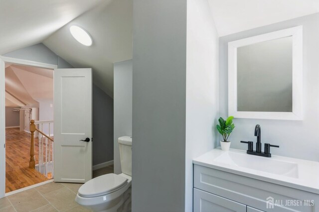 bathroom featuring vanity, lofted ceiling, and toilet