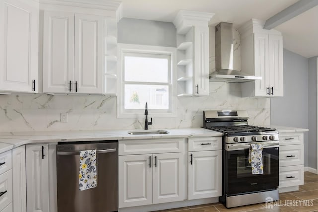 kitchen with wall chimney range hood, appliances with stainless steel finishes, white cabinetry, and a sink