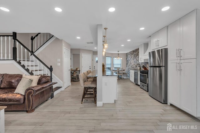 103 Rumford Way, Manalapan, NJ 07726 - kitchen with appliances with stainless steel finishes, open floor plan, a breakfast bar, light wood-style flooring, and white cabinets