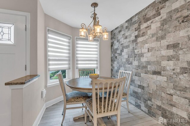 103 Rumford Way, Manalapan, NJ 07726 - dining area featuring an accent wall, a chandelier, baseboards, and light wood-type flooring