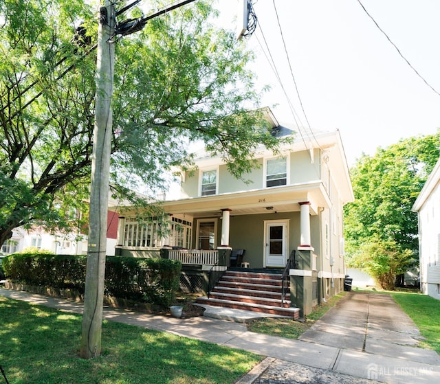 american foursquare style home featuring a porch, driveway, and stucco siding