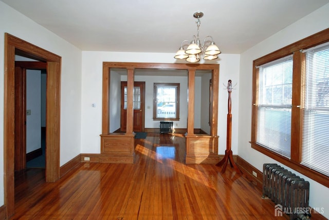 dining room featuring an inviting chandelier, radiator heating unit, and dark hardwood / wood-style flooring