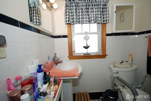 bathroom with sink, tile walls, and toilet