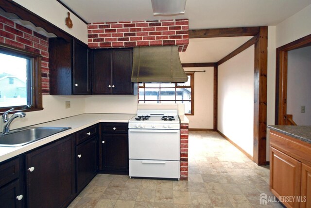 kitchen with brick wall, white gas range, sink, and exhaust hood