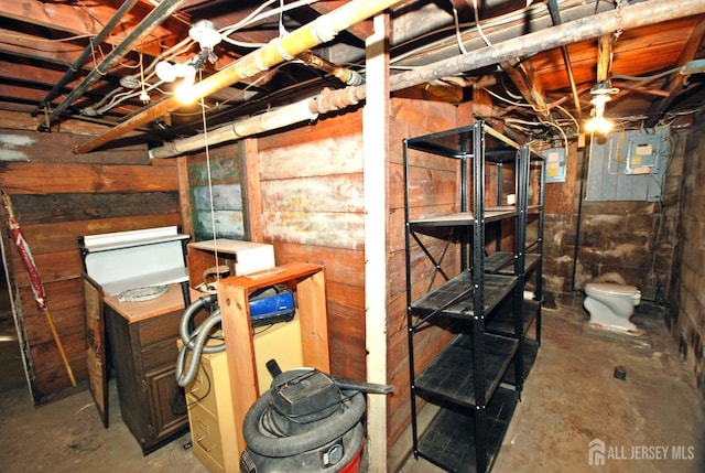 basement featuring electric panel and wood walls