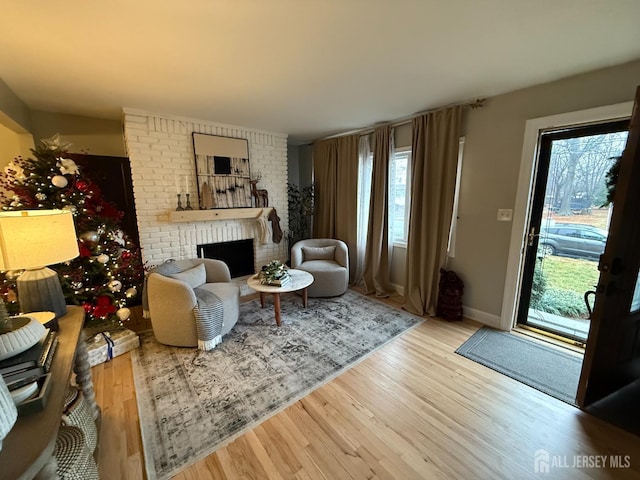 living room with wood-type flooring and a brick fireplace